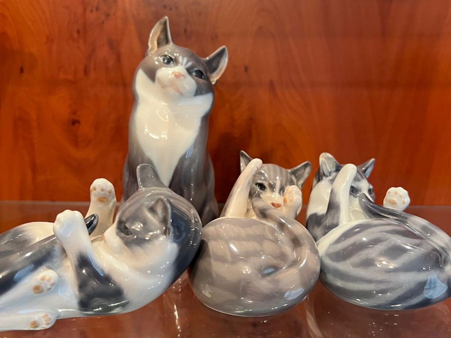 Four Royal Copenhagen china cats, three at play and one seated