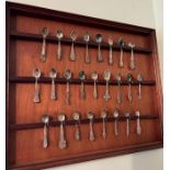 Twenty Five collector spoons on a wooden display case