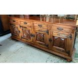 A long hardwood sideboard on bun feet consisting of four drawers and four cupboards with wrought