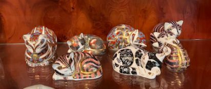 Seven Royal Crown Derby paperweight cats (Largest 12cm x 6cm)