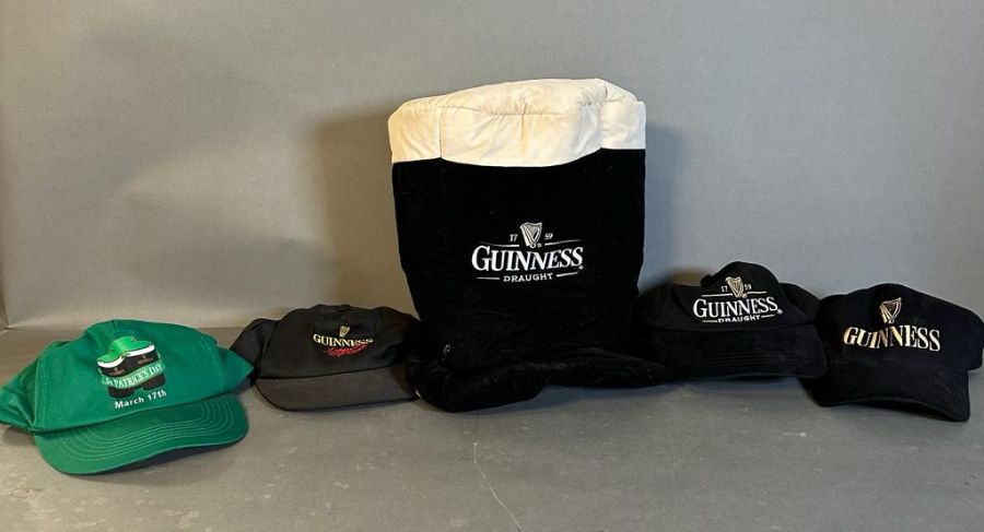 A collection of four Guinness baseball caps and a Guinness top hat