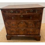A walnut chest of drawers, two over three with brass drop handles and on bracket feet (Approximate