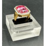 A Fashion ring in gold marked 18 with central pink stone and white stone surround. Approximate Total