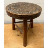 An Arts and Crafts style stool with carved circular top on tripod legs (H28cm Dia24cm)