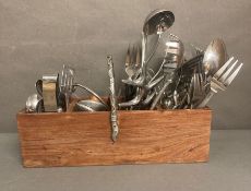 A large selection of white metal cutlery in a wooden cutlery holder