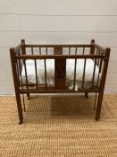 An antique dolls cot, with bedding