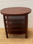 An oval side table with central shelves 60cm x 63cm