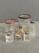 A selection of glass and white metal topped perfume bottles and enamel top jars, some silver