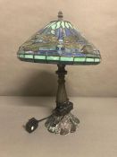 A blue and turquoise stained glass Tiffany style lamp with dragon fly detail