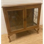 A two shelf display cabinet with leaded glazed doors and sides on cabriole legs