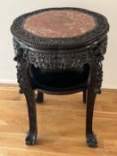 A Chinese ornate red marble topped table on ball and claw feet with shelf under and carved