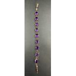 Marked 14 carat with a barrel clasp and safety clip a bracelet with 9 oval amethyst equally