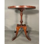 An oval mahogany occasional table with string inlay top and piecrust rim on turned central