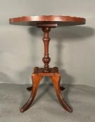 An oval mahogany occasional table with string inlay top and piecrust rim on turned central