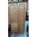 A single pine wardrobe with four drawers and cupboard.