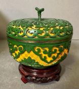 A small Chinese lidded pot in green and gold on a plinth