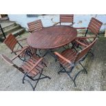 A Teak Garden circular table with wrought iron folding legs along with six matching chairs.