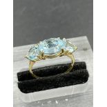 A three stone blue topaz ring with a central oval cut topaz weighing an estimated 3.00ct with a