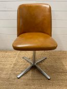 A Mid-Century swivel office chair upholstered in brown faux leather