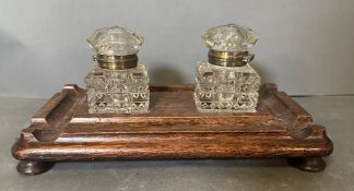 A pair of cut glass ink wells on an oak stand