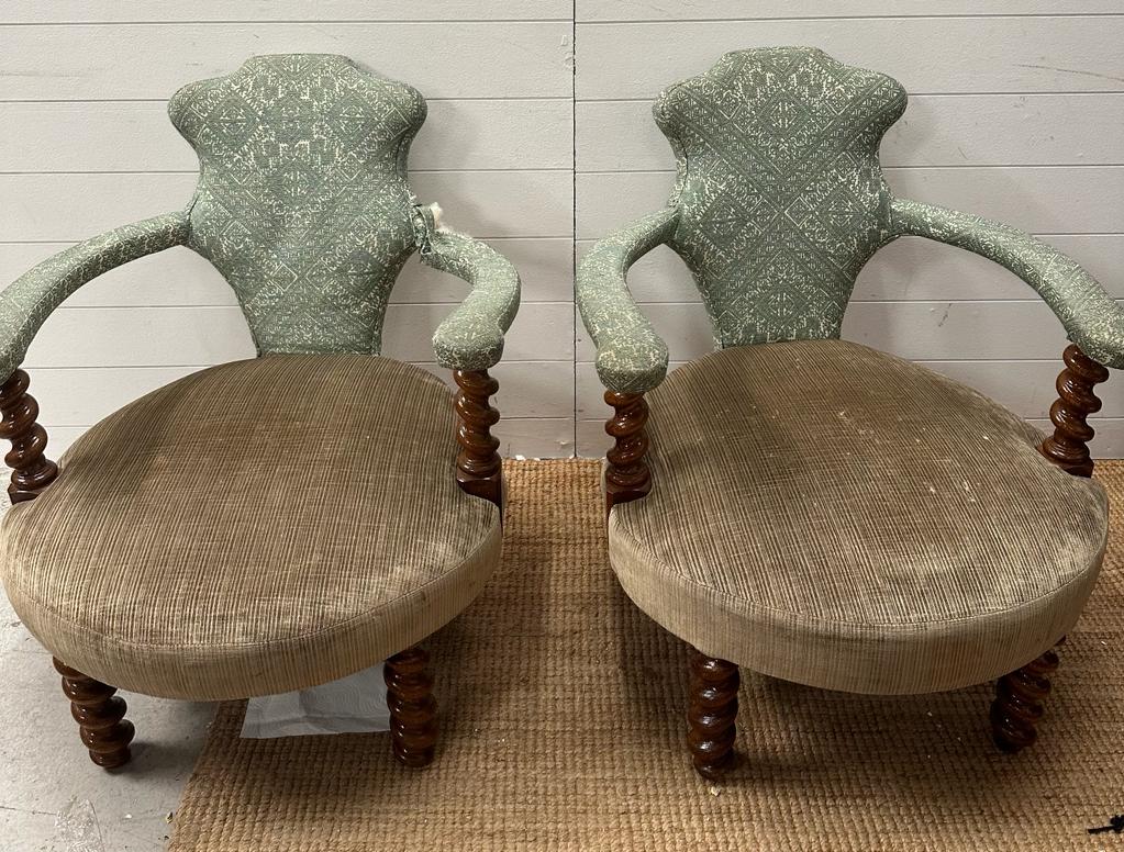 A pair of oak framed Victorian salon chairs upholstered in green with barley twist legs and arm