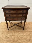 A mahogany three drawer side table on fluted legs with faux book detail