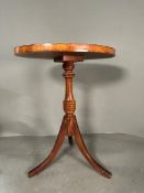 An oval mahogany occasional table with brown leather top and pie crust edge on tripod splayed