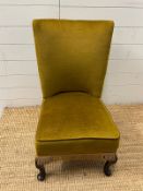 A green upholstered slipper chair on cabriole legs