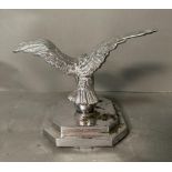 A cast metal eagle on ball on two step mount, possibly car or truck mascot.