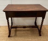 An oak Arts and Crafts style side table with two drawers to ends on barley twist legs and cross