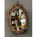 A wooden framed gold painted oval wall hanging mirror in the Rococo style (49cm x 73cm)