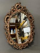 A wooden framed gold painted oval wall hanging mirror in the Rococo style (49cm x 73cm)