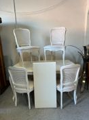 A white painted single leaf dining table with six cane backed chairs upholstered in white (H74cm