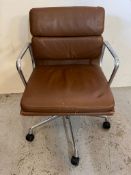 A Charles Eames desk chair in chrome and leather with signs of wear.