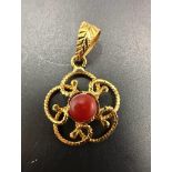 An Asian gold pendant with red central stone, marked as 21ct