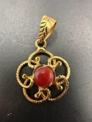 An Asian gold pendant with red central stone, marked as 21ct