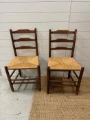 A pair of oak ladder back chairs with rush seats
