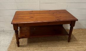 A pine stained coffee table with shelf under (H49cm W99cm D48cm)