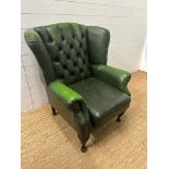 A green leather button back wing back arm chair on cabriole legs H100cm W80cm D70cm