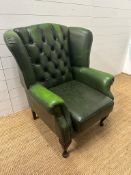 A green leather button back wing back arm chair on cabriole legs H100cm W80cm D70cm