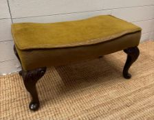 A green upholstered foot stool on cabriole legs