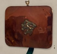 A copper wall hanging with brass lion detail