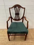 A mahogany shield back open armchair upholstered in green