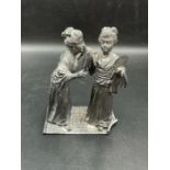 A white metal statue of two Geisha girls