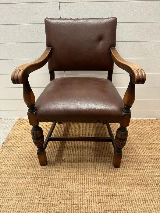 An oak brown leather studded upholstered open armchair on carved legs