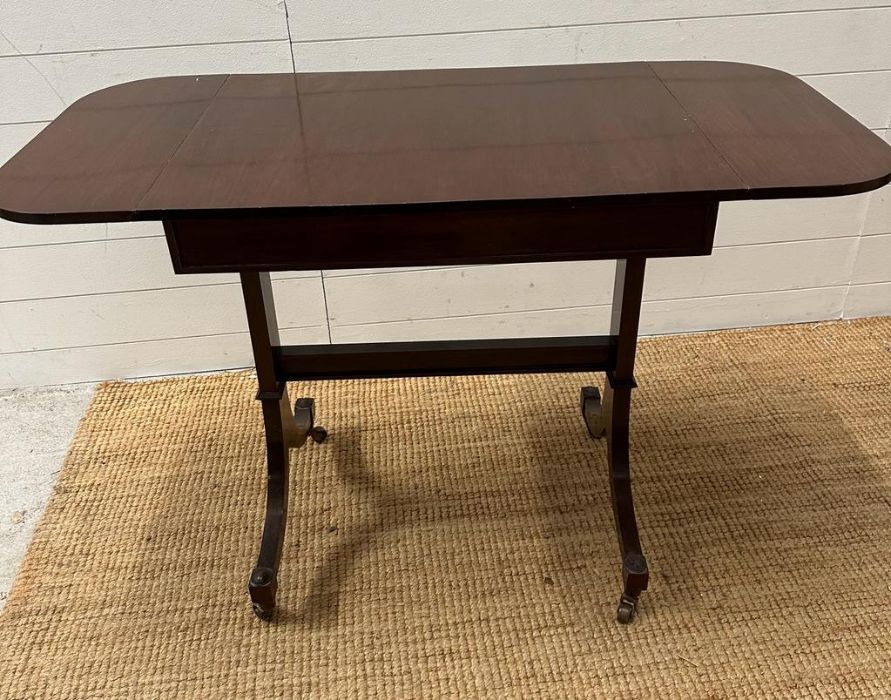 A mahogany drop leaf occasional table on splayed legs and castors (H73cm W108cm D51cm)