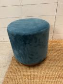 A contemporary foot stool upholstered in aqua velvet