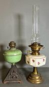 A Victorian brass oil lamp with a white ceramic well with floral detail and a cast iron based oil