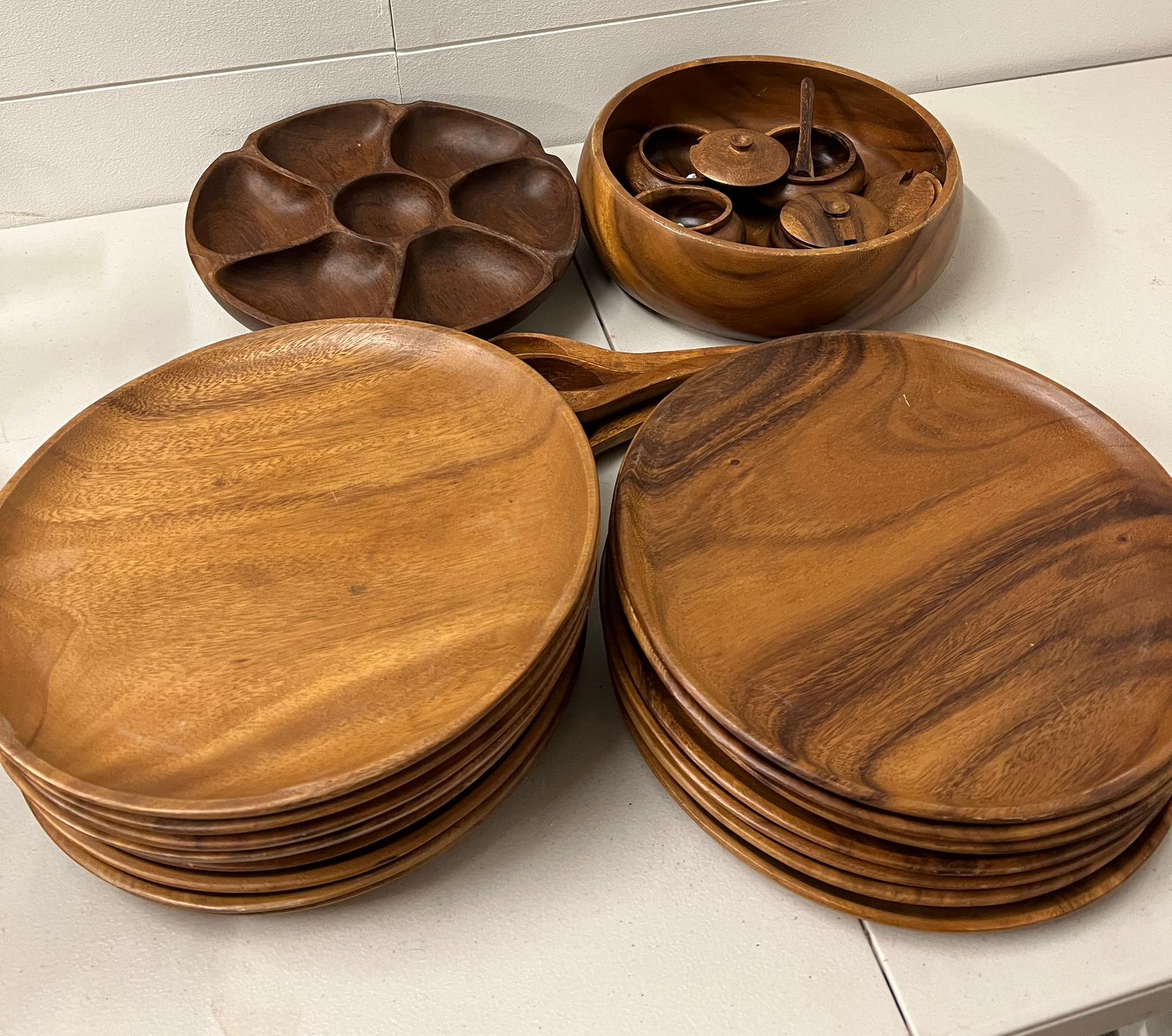 A wooden dinner set comprising of sixteen wooden plates, one serving bowl, four sauce pots and