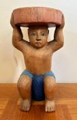 A wooden painted carving of a child holding a plinth (H38cm)